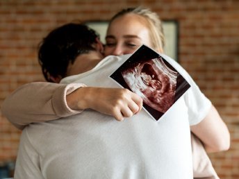 Joyful couple holding ultrasound (USG) report together.
