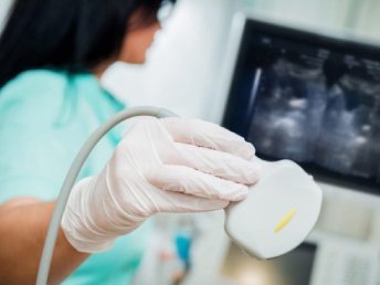 Close-up view of a radiologist holding an ultrasound probe during a medical examination.