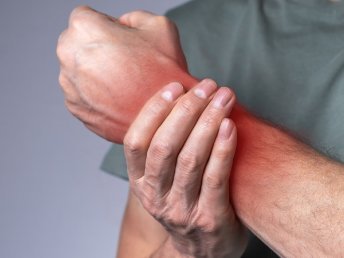 A person holding their wrist, suggesting discomfort or pain.