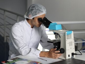 Pathologist conducting pathology cam testing, looking through a microscope.